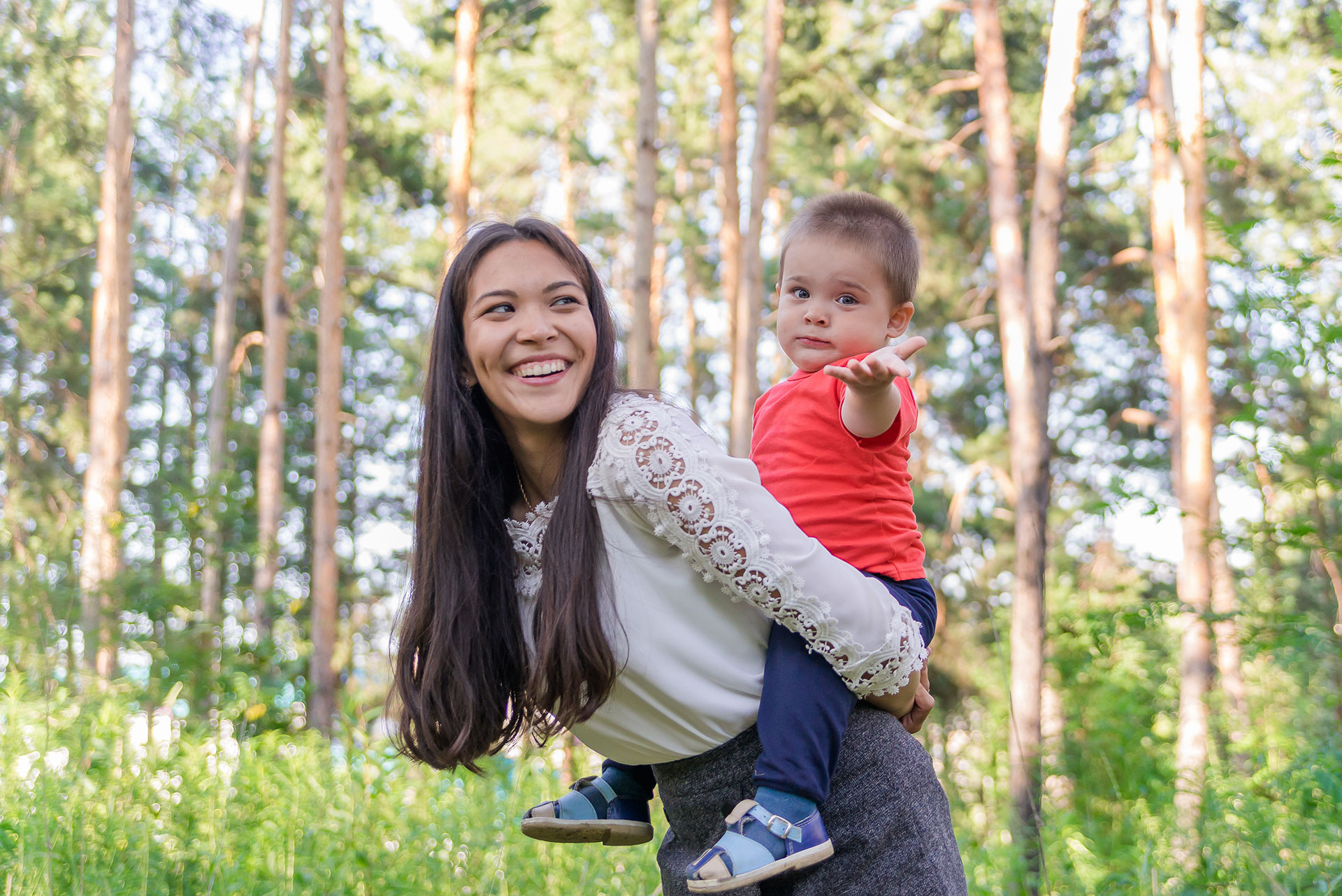 A happy young mother plays and has fun with her little son in the sun on a warm spring or summer day. The concept of a happy family, motherhood. Mother and child walk